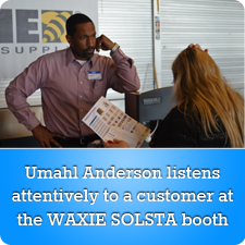 Umahl Anderson listens attentively to a customer at the WAXIE SOLSTA booth