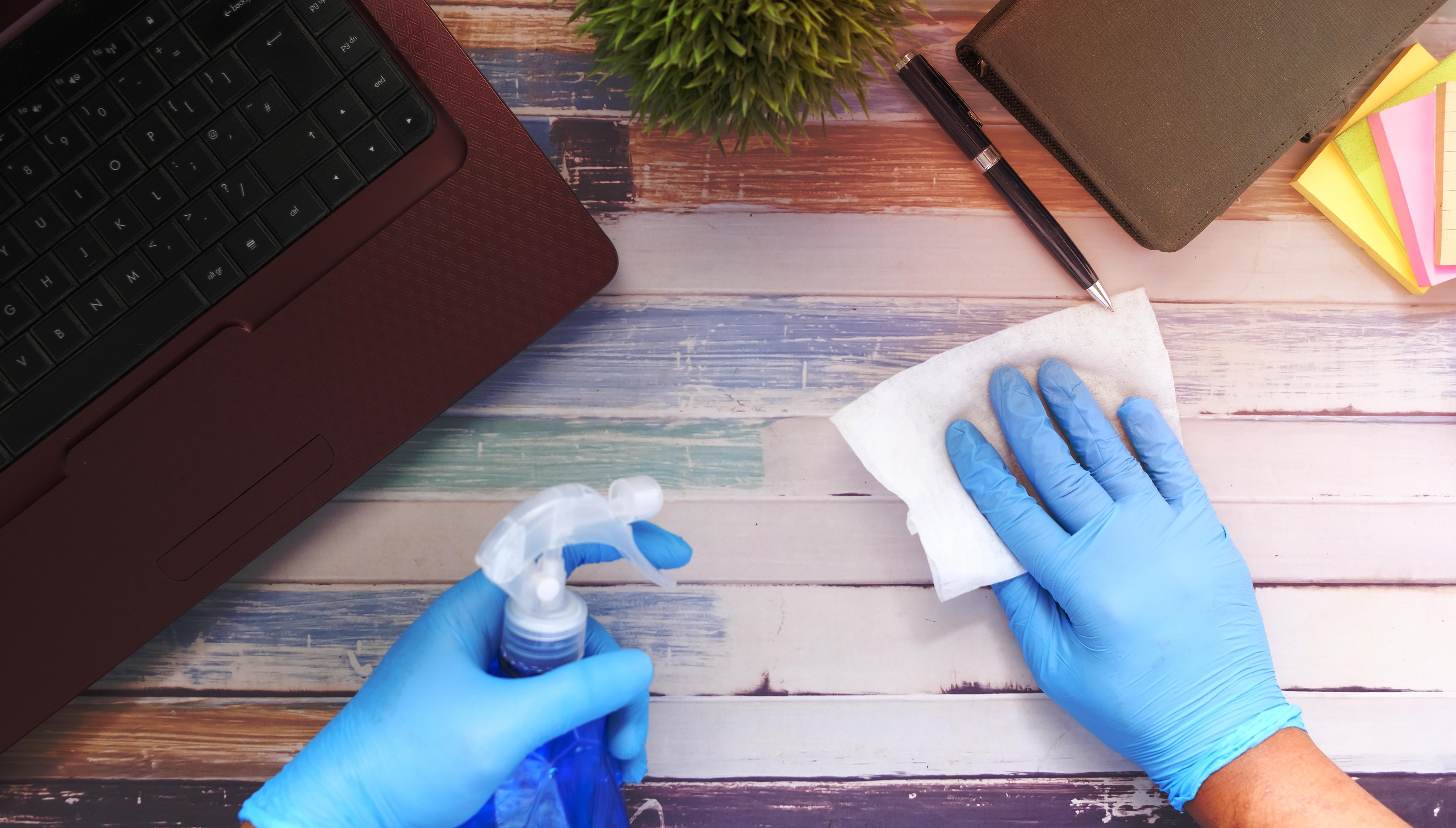gloved hands cleaning desk