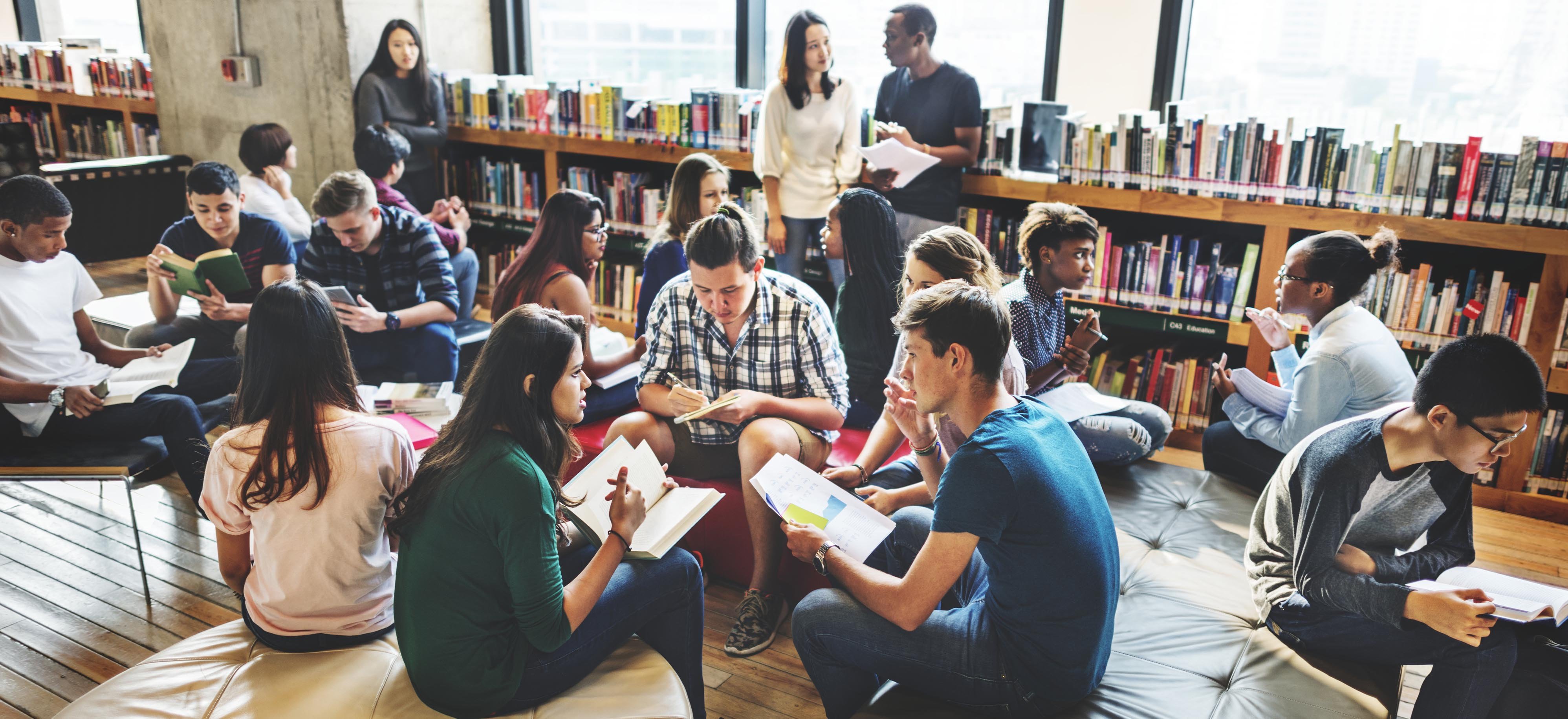 group of college students gathered in library studying together