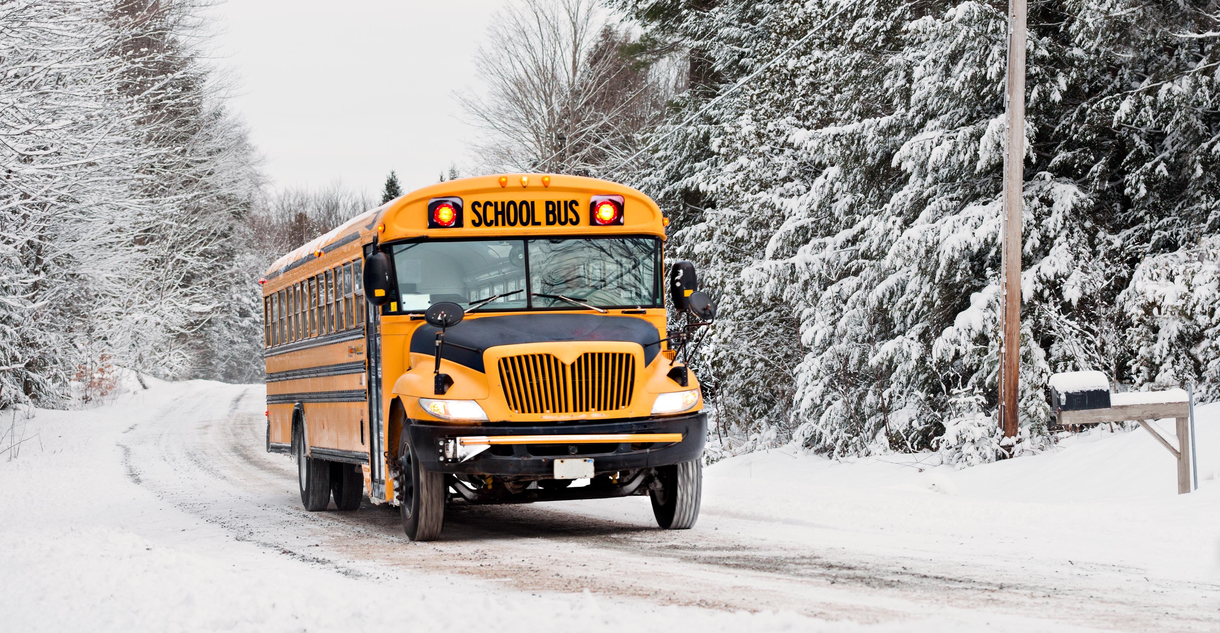 school bus driving on snow covered road during winter